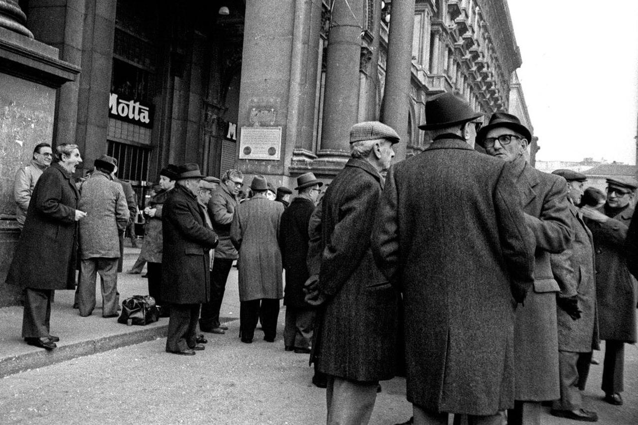 Piazza del Duomo, Milan, January 1983 — men in overcoats gathered under the arcades by the Motta sign, arguing the morning away. This was the winter the city talked its rossonero half out of Serie B: by June, Castagner's Milan had won the cadetteria and come home to Serie A.