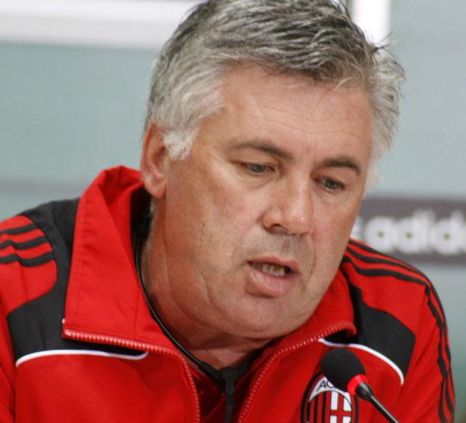 Carlo Ancelotti facing the press in the Milan tracksuit, 1 August 2008 — head coach across the whole of the year, from the Arsenal elimination to the Ronaldinho rebuild.