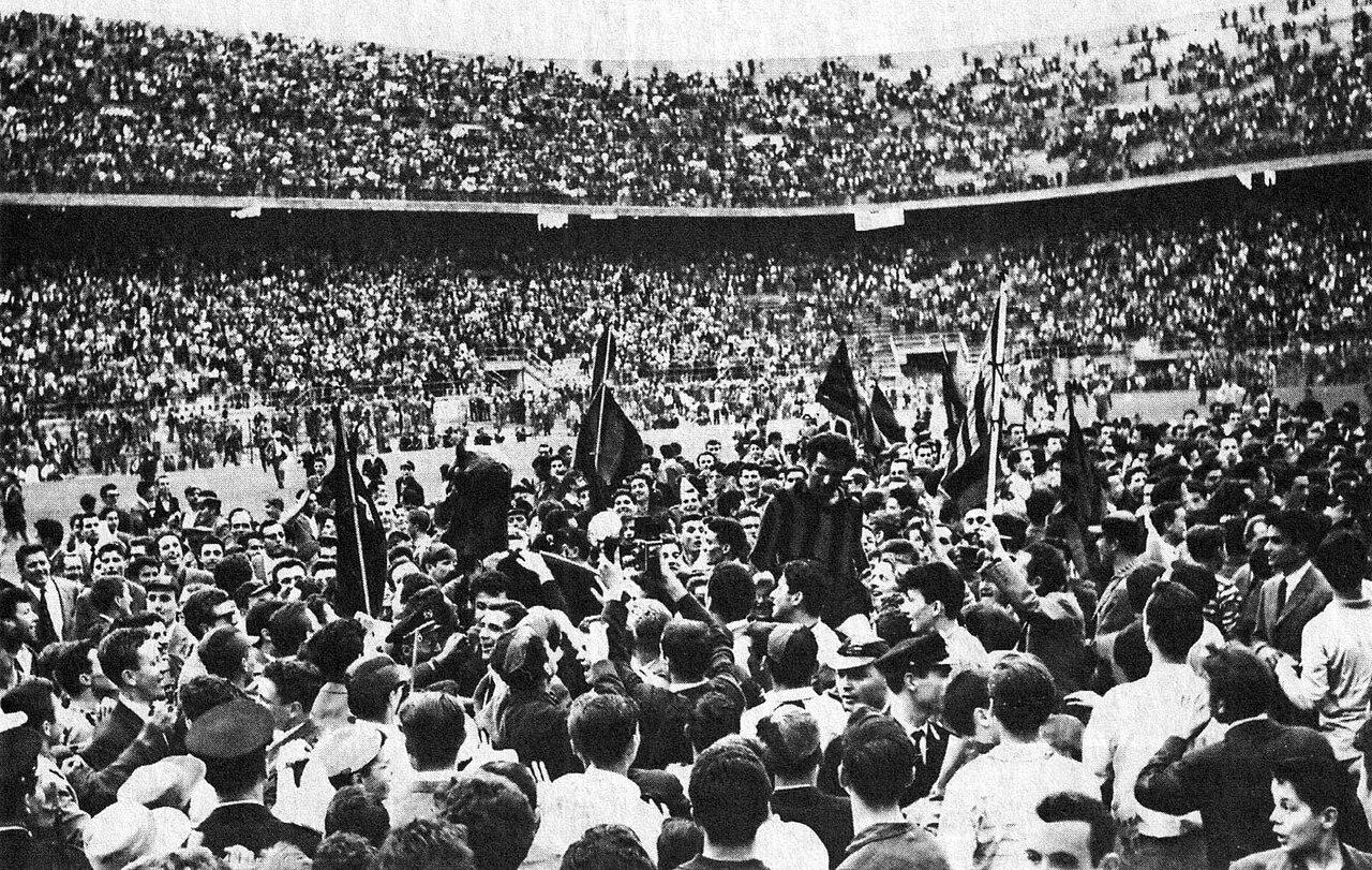 San Siro, 2 June 1959: the crowd pours onto the pitch as Milan thrash Udinese 7-0 on matchday 33 and make the seventh scudetto mathematically certain — flags aloft, players carried on shoulders.