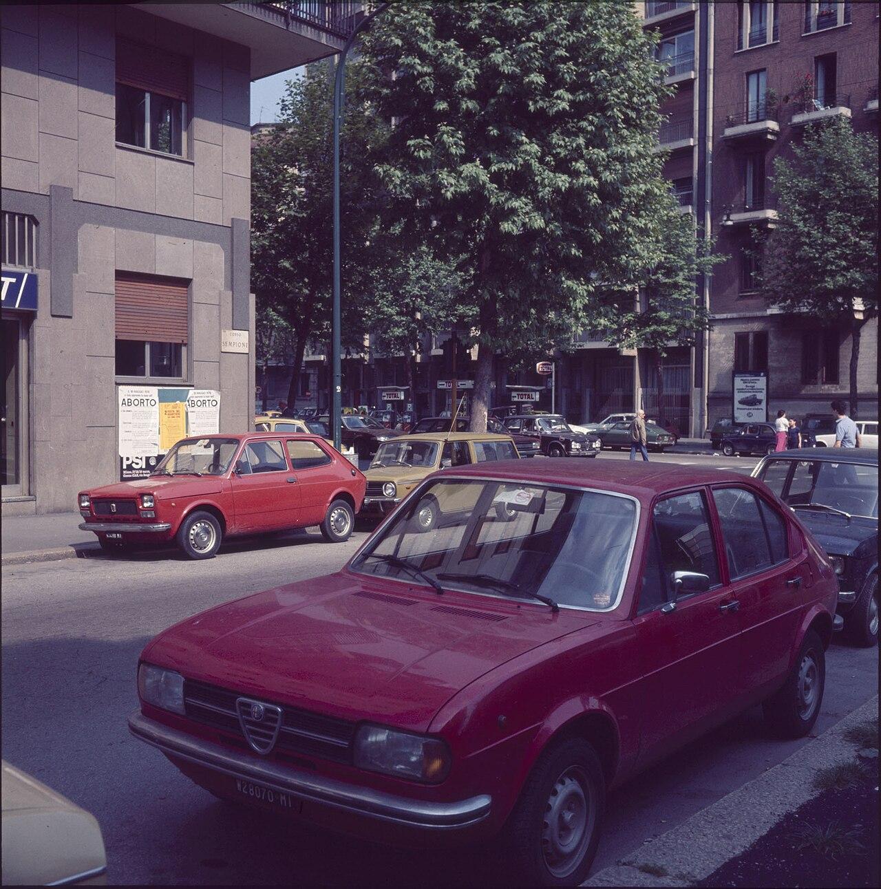 Corso Sempione, Milan, 1978, photographed by Paolo Monti — an Alfasud and a Fiat 127 at the kerb, PSI posters about the new abortion law on the wall. The city as it looked in the anxious late seventies, while Liedholm's Milan rebuilt toward the tenth scudetto.