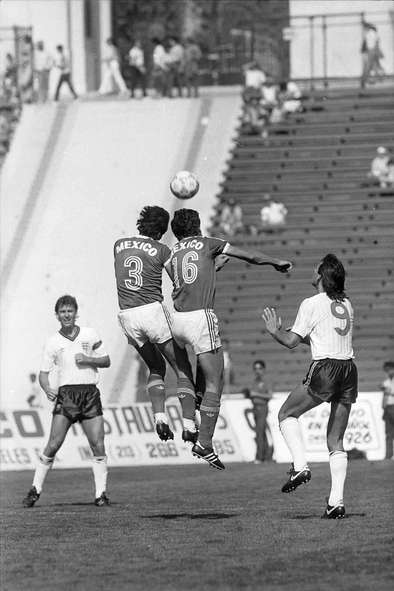 Two Mexican defenders climb above England's number 9 — Mark Hateley — at the Los Angeles Memorial Coliseum, May 1986, Bryan Robson watching from the left. By then 'Attila' was Milanese property: the battering-ram signed from Portsmouth in 1984 whose derby header over Collovati had entered rossonero folklore, and who, with Ray Wilkins, formed the English spine of Liedholm's rebuilding Milan through 1985.