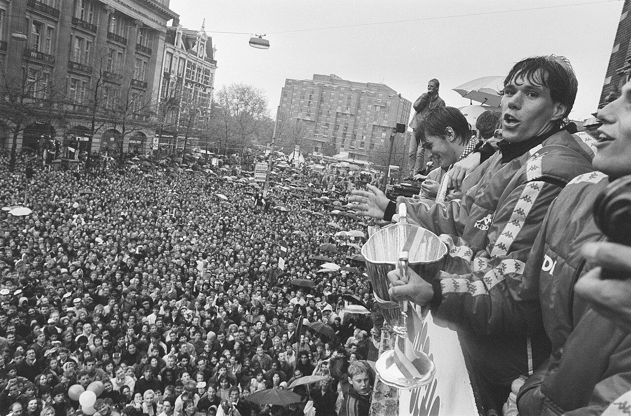 Marco van Basten holds the Cup Winners' Cup aloft on the balcony of Amsterdam's Stadsschouwburg, 14 May 1987 — the night after his goal beat Lokomotive Leipzig in Athens. It was his farewell gift to Ajax: weeks later the coldest finisher of his generation arrived in Milan.